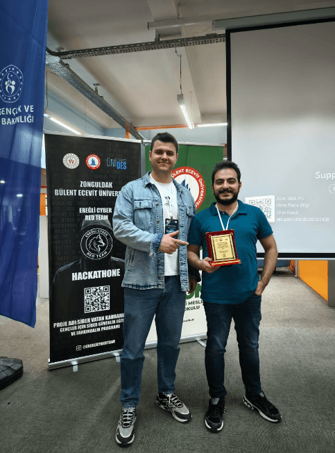 İki ekip üyesi hackathon birincilik plaketiyle poz veriyor.